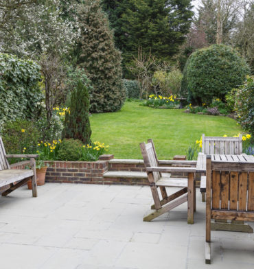 Wooden bench, table and chairs on a patio in a London suburban garden - Big Easy Patio